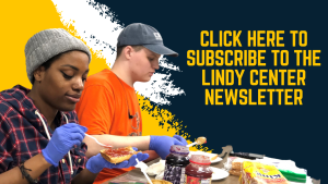 Image of two students making peanut butter and jelly sandwiches - one student has dark skin and a grey beanie and the other has light skin and a gray hat. They are both wearing purple gloves. THe text on the image reads 'For up-to-date news, event announcements, and volunteer opportunities